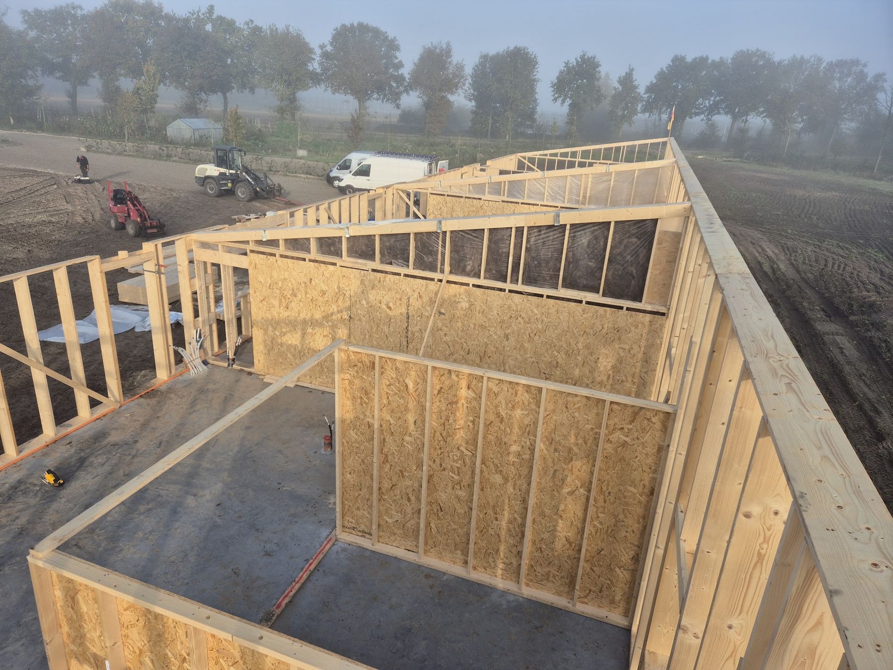 Het houtskelet van een nieuw gebouw met OSB-wanden, van bovenaf gezien in de ochtendmist