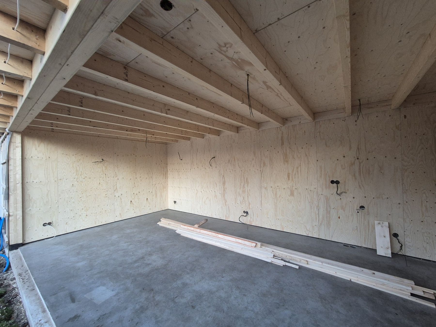 Het interieur van een nieuw houten gebouw met zichtbare dakbalken en multiplex wanden